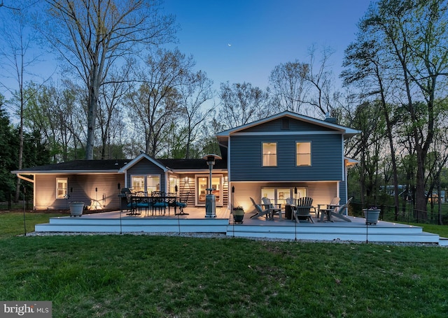 back of property with a wooden deck and a yard