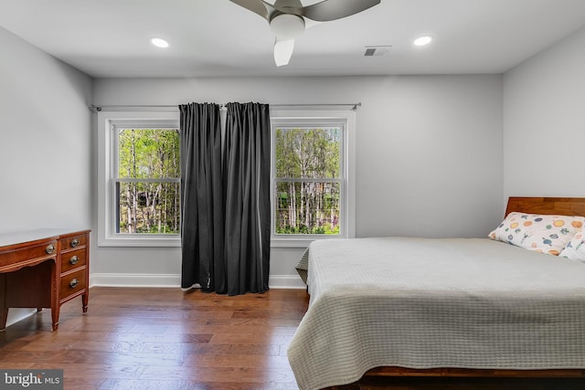 bedroom featuring ceiling fan, wood finished floors, multiple windows, and visible vents