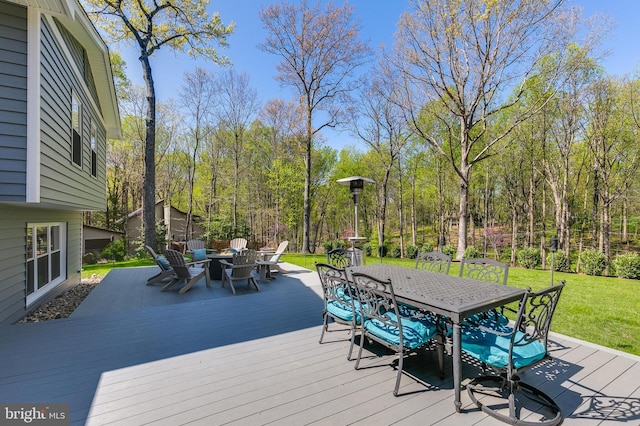 wooden terrace with outdoor dining space and a lawn