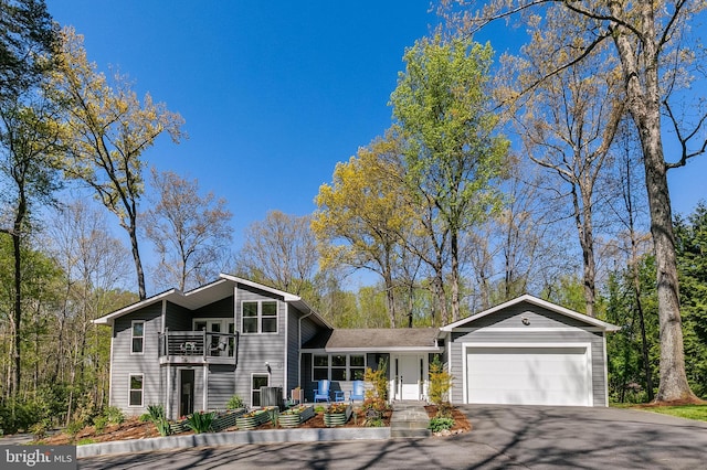 view of front of house featuring a garage, a balcony, and aphalt driveway