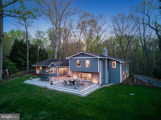 rear view of property with a lawn, fence, a view of trees, and a chimney