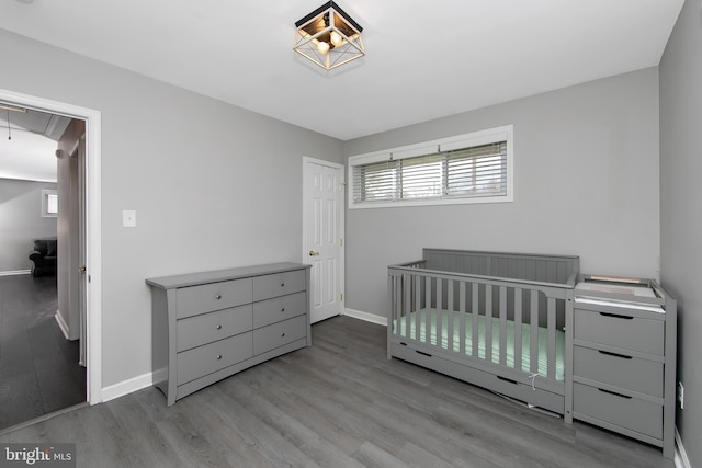bedroom featuring attic access, baseboards, and wood finished floors