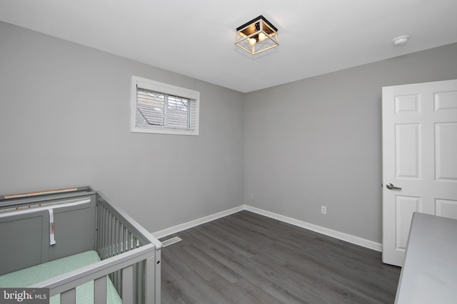 unfurnished bedroom with baseboards and dark wood-style floors