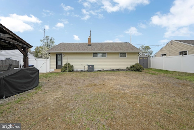 back of house with a storage shed, a fenced backyard, central AC unit, a gate, and a chimney