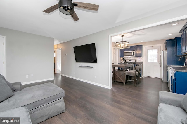 living area with ceiling fan with notable chandelier, baseboards, dark wood-style floors, and recessed lighting