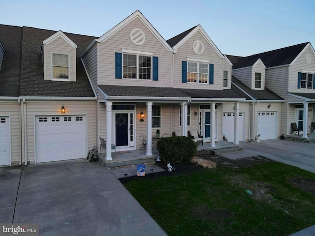 view of front facade featuring concrete driveway, a shingled roof, and covered porch