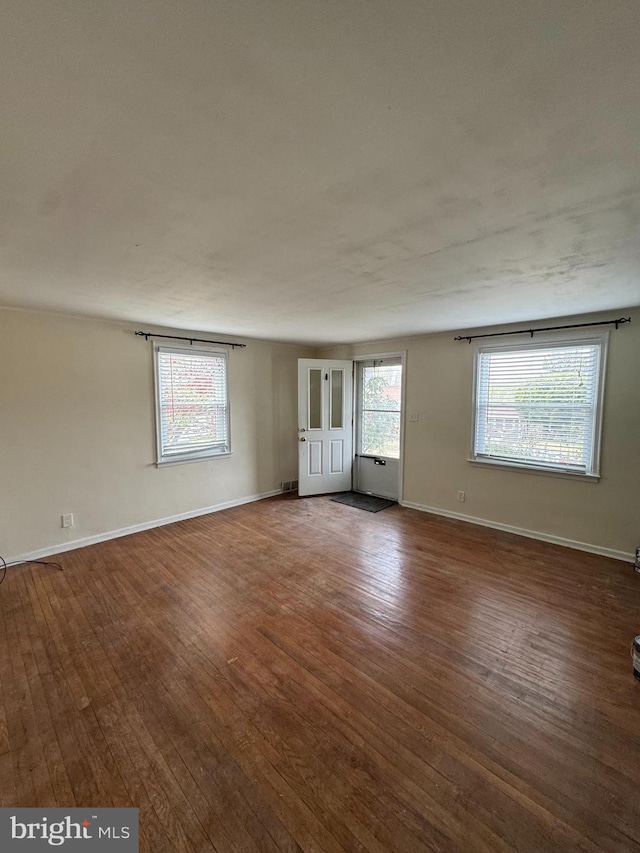 spare room with baseboards, wood finished floors, and plenty of natural light