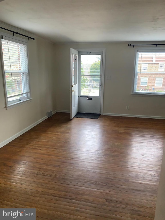 spare room featuring baseboards, wood finished floors, and visible vents