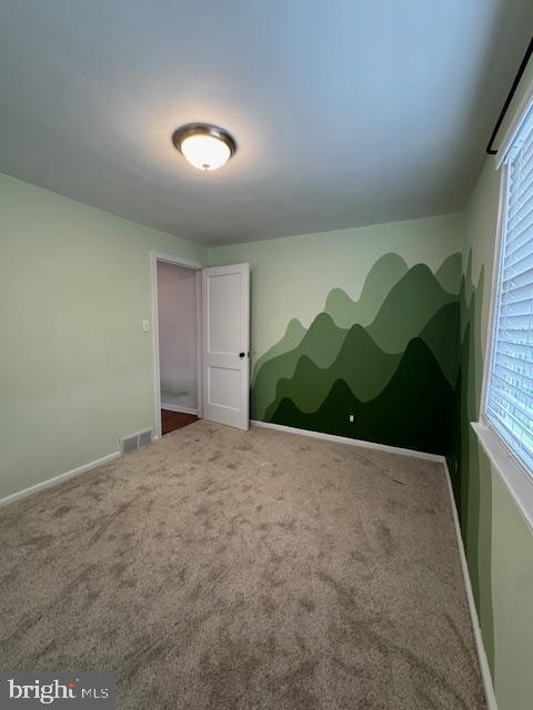 spare room with visible vents, carpet flooring, and a wealth of natural light
