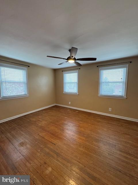 spare room with hardwood / wood-style floors, a ceiling fan, and baseboards