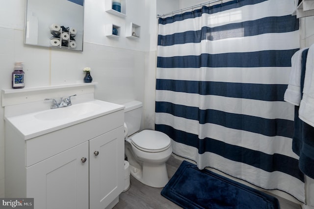 full bath with vanity, toilet, a shower with shower curtain, tile walls, and wood finished floors