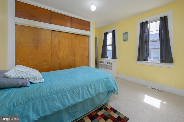 bedroom featuring radiator, carpet, baseboards, visible vents, and a closet