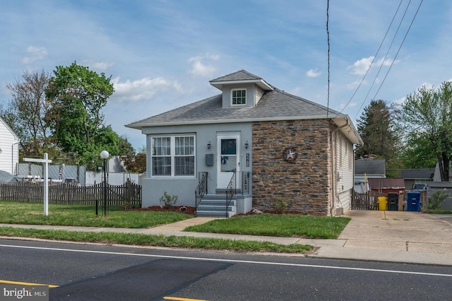 view of front of property featuring fence, a shingled roof, stone siding, stucco siding, and concrete driveway