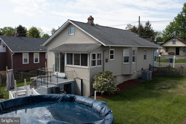 rear view of property with a lawn, a shingled roof, fence, and a chimney