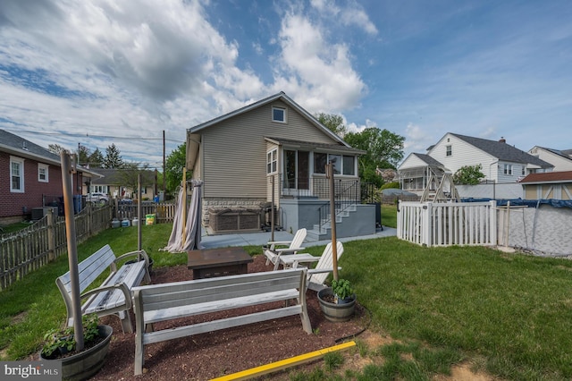rear view of house with a fenced backyard, stone siding, a yard, and a residential view