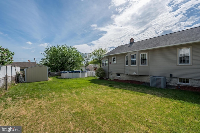 view of yard featuring a storage shed, fence, central AC unit, and a fenced in pool