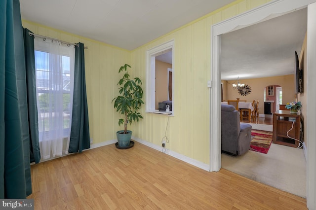 spare room with baseboards, arched walkways, wood finished floors, and a chandelier