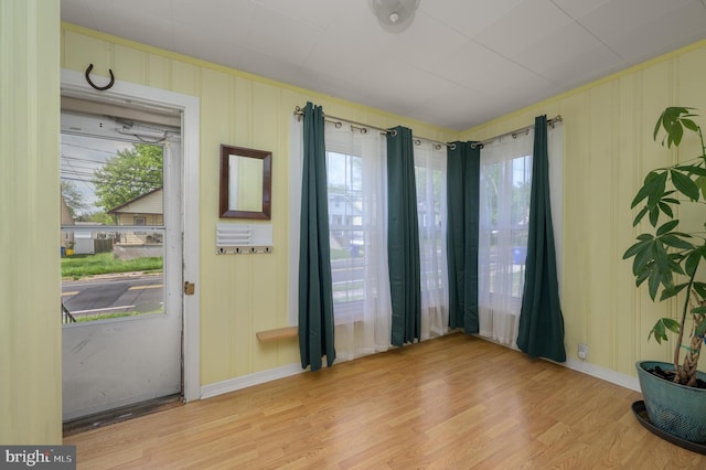 interior space with baseboards, light wood finished floors, and a healthy amount of sunlight