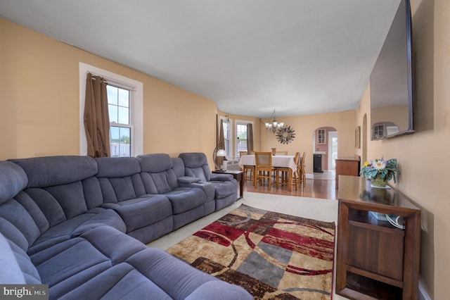 living area with arched walkways, an inviting chandelier, and wood finished floors