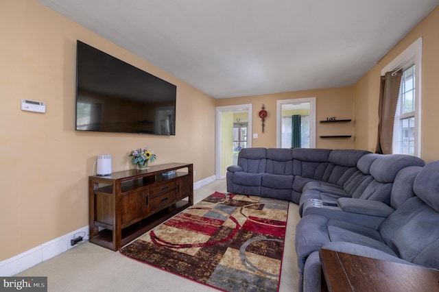 carpeted living area with baseboards and a healthy amount of sunlight