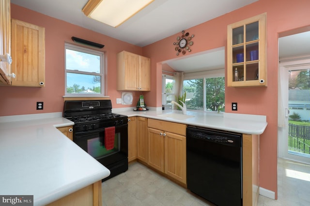 kitchen with a healthy amount of sunlight, a sink, black appliances, glass insert cabinets, and light brown cabinets