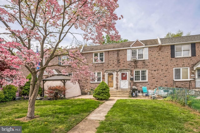 view of front of property with fence, a gazebo, brick siding, and a front yard