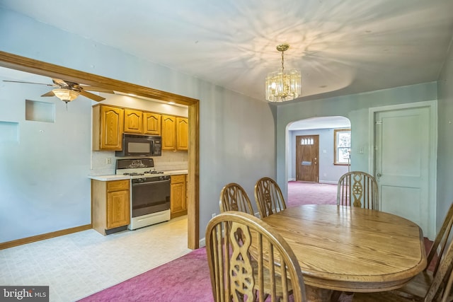 dining area with arched walkways, baseboards, ceiling fan with notable chandelier, and light floors
