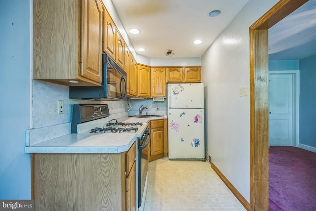 kitchen with light countertops, freestanding refrigerator, brown cabinetry, and gas range