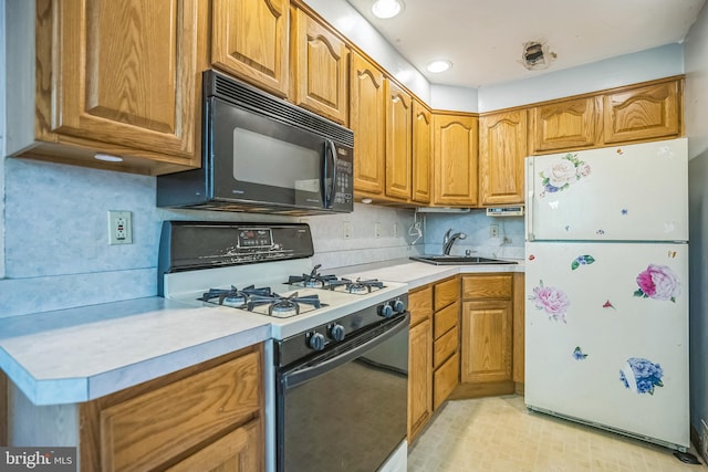 kitchen featuring gas range, black microwave, light countertops, a sink, and freestanding refrigerator