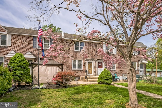 multi unit property featuring brick siding, a gazebo, and a front lawn