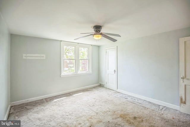 carpeted empty room with ceiling fan, visible vents, and baseboards