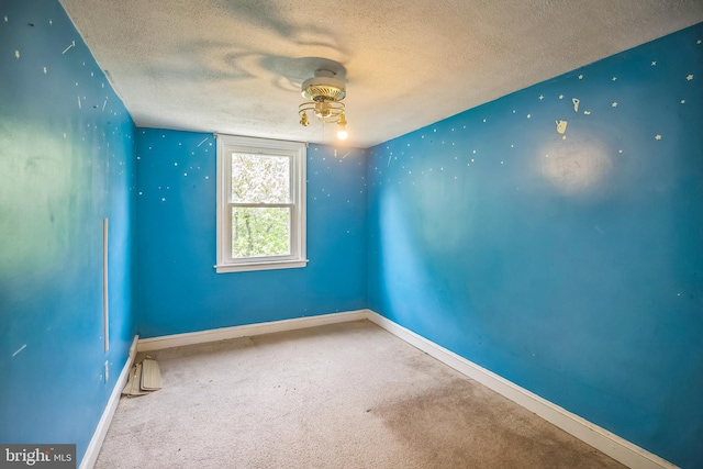 carpeted empty room with baseboards, a ceiling fan, and a textured ceiling