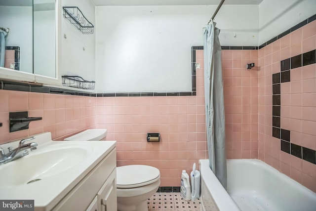 full bathroom featuring tile walls, wainscoting, shower / tub combo, vanity, and toilet