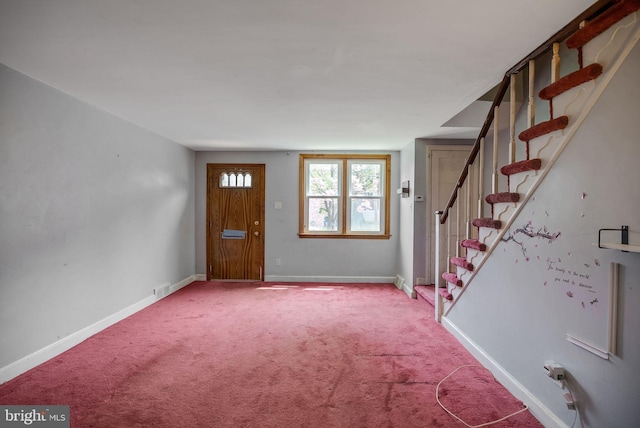 carpeted entrance foyer featuring stairway and baseboards