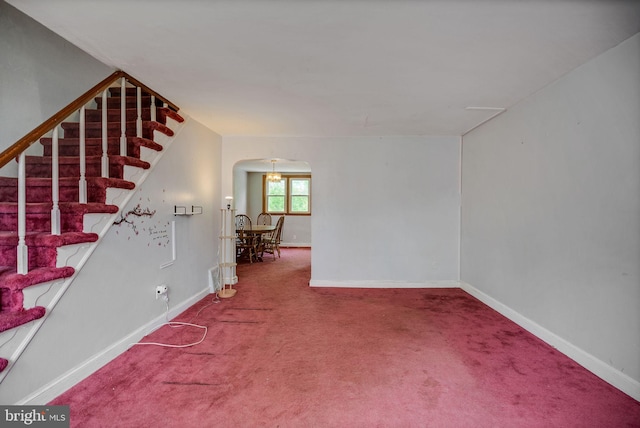 unfurnished room with carpet floors, arched walkways, and baseboards