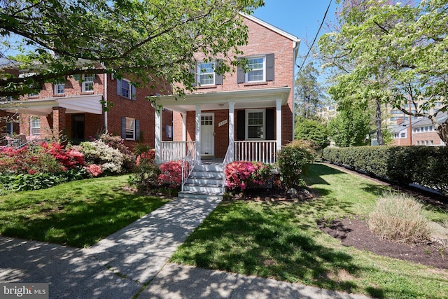view of front facade featuring a front yard, brick siding, and covered porch