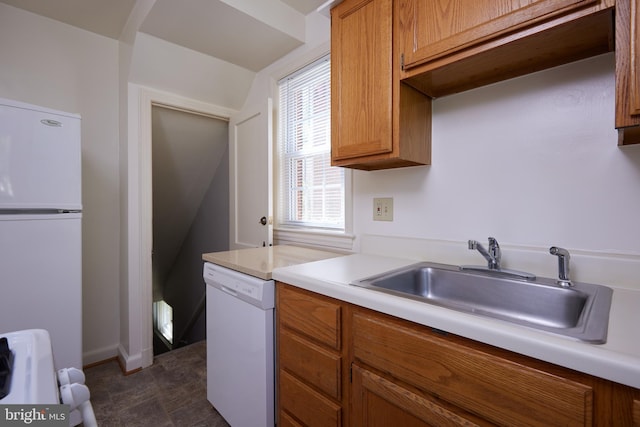 kitchen with light countertops, brown cabinets, a sink, and white appliances