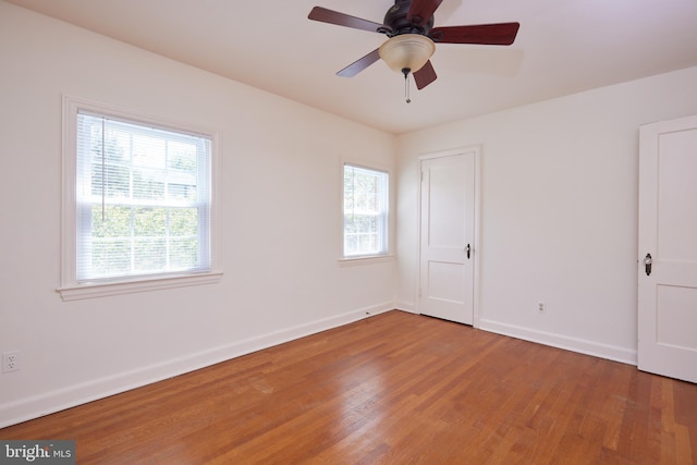 empty room with baseboards, a ceiling fan, and wood finished floors