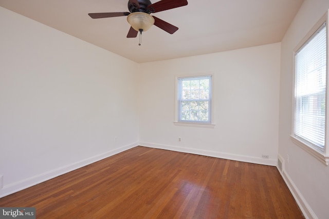 empty room featuring baseboards, a ceiling fan, visible vents, and wood finished floors