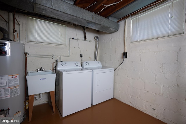 clothes washing area featuring a sink, gas water heater, washer and clothes dryer, laundry area, and concrete block wall