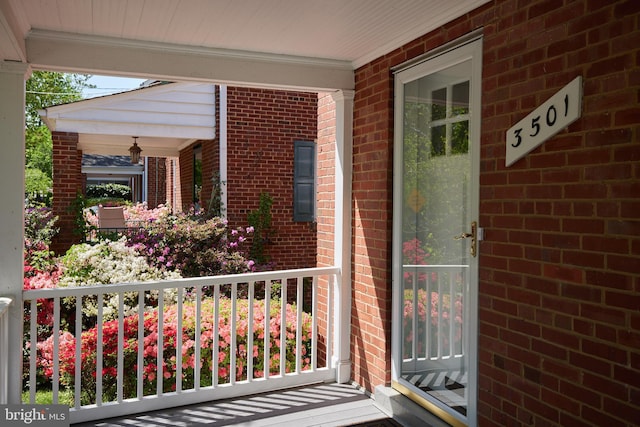 property entrance featuring covered porch and brick siding