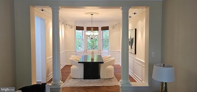 dining room featuring wood finished floors, a decorative wall, and wainscoting