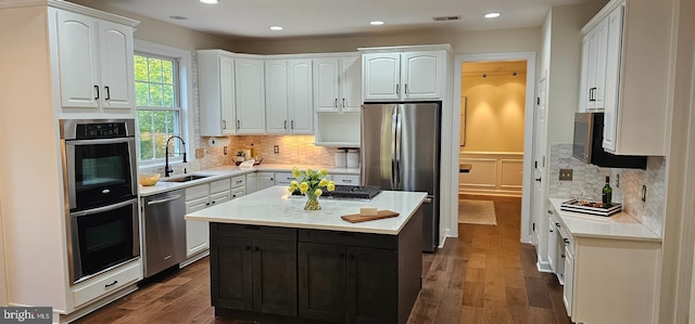 kitchen with white cabinets, stainless steel appliances, a sink, and dark wood-type flooring