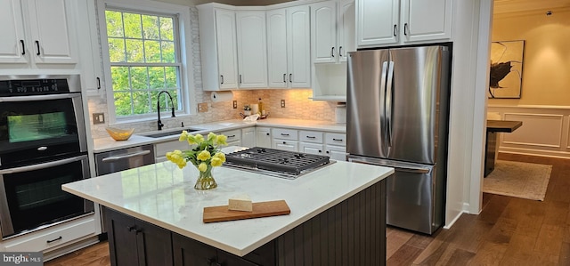 kitchen with dark wood-style floors, a sink, backsplash, white cabinetry, and appliances with stainless steel finishes
