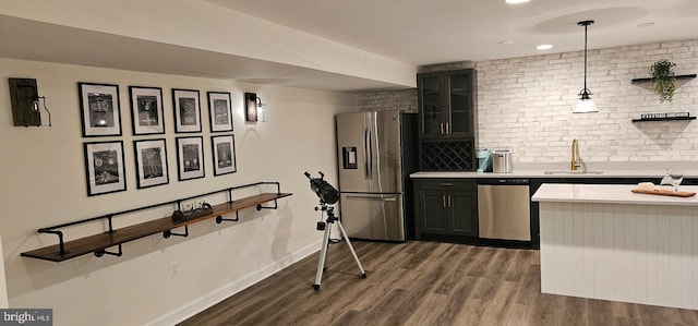 kitchen featuring stainless steel appliances, a sink, dark wood finished floors, glass insert cabinets, and light countertops