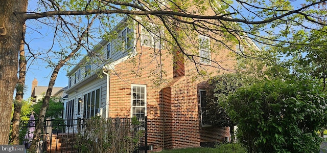 view of side of property featuring brick siding and fence