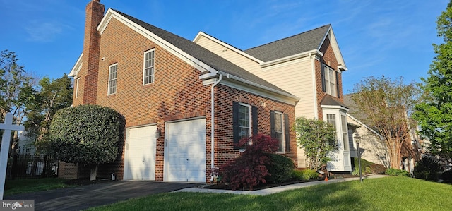 view of property exterior with a chimney, aphalt driveway, a yard, an attached garage, and brick siding
