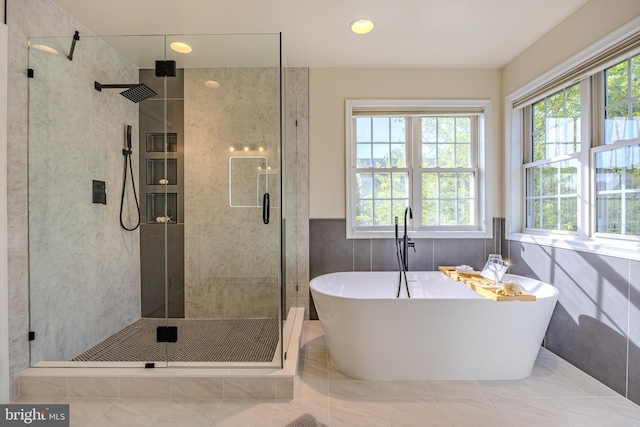 bathroom with tile walls, a freestanding tub, and a stall shower