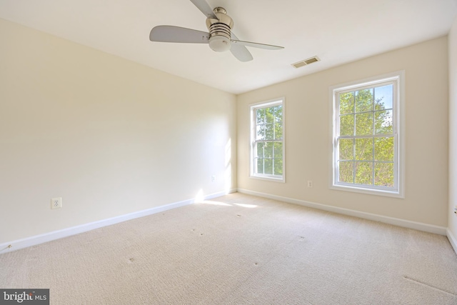empty room featuring baseboards, visible vents, a ceiling fan, and light colored carpet