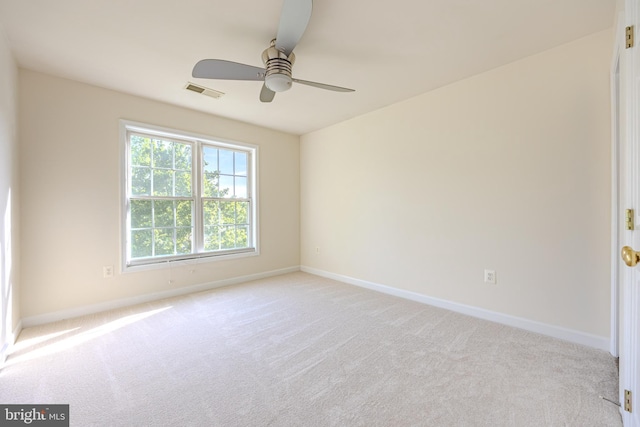 spare room featuring a ceiling fan, visible vents, light colored carpet, and baseboards